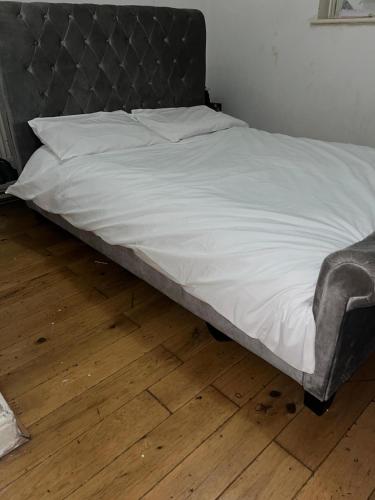 uma cama com cabeceira metálica e lençóis brancos em Home 2 Home em Londres