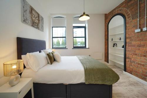 a bedroom with a bed and a brick wall at Stylish & Elegant city centre apartment in Leeds