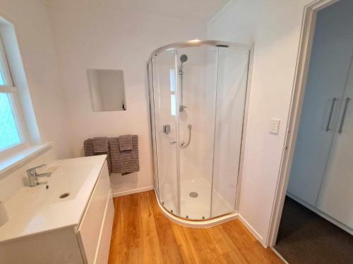 biała łazienka z prysznicem i umywalką w obiekcie 3bdrm plus Sleepot Home, w mieście Nelson