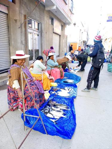 a group of people sitting on a sidewalk with tarps at Suma Qamaña in Copacabana