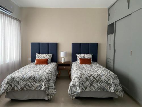 a bedroom with two beds and a table and a window at Departamento colonia Carrizal in Villahermosa