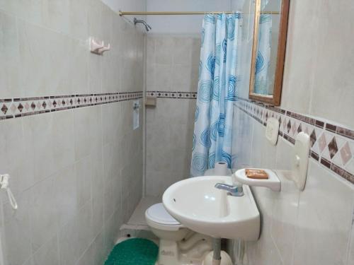 Baño blanco con lavabo y aseo en Hostal Casablanca Santa Marta, en Santa Marta