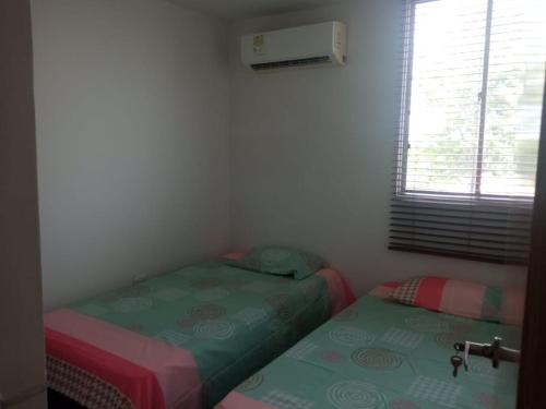 two twin beds in a small room with a window at Cómodo apartamento cerca al mar in Coveñas