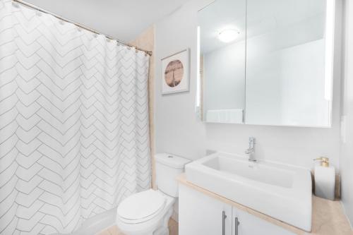 a white bathroom with a toilet and a sink at Luxury Downtown Toronto 2 Bedroom Suite with City and Lake Views and Free Parking in Toronto