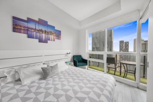 a white bedroom with a bed and a large window at Luxury Downtown Toronto 2 Bedroom Suite with City and Lake Views and Free Parking in Toronto