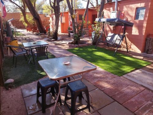 a patio with two tables and stools and a grill at Hostal Perita in San Pedro de Atacama