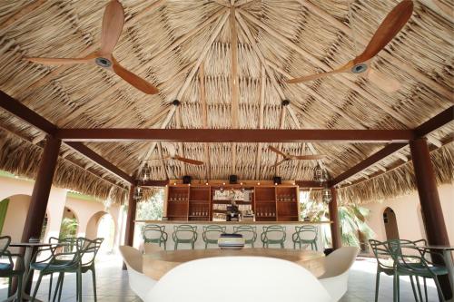 a restaurant with a straw roof with chairs and a bar at The Lizard Boutique Hotel in Kralendijk