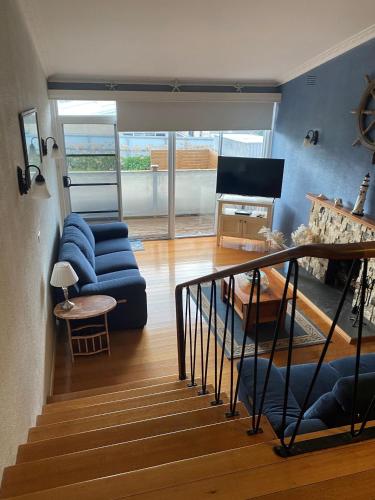 a living room with a blue couch and a piano at Ahoy Family Beach Escape in Portarlington