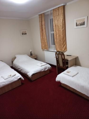 a room with two beds and a chair in it at Pałac Lasów in Pieńsk