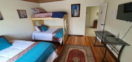 a small room with two beds and a television at Casa Hostal Sweet Home in Bogotá