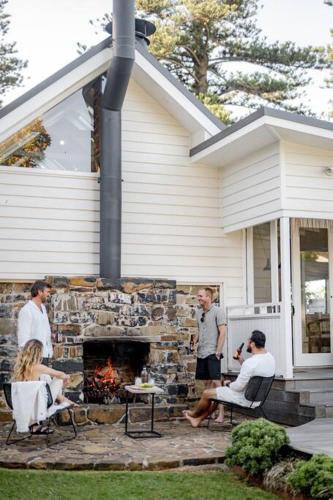 a group of people sitting around a stone fireplace at Soul of Gerringong Farmhouse in Gerringong