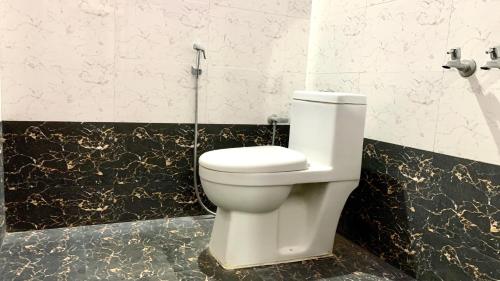 a toilet in a bathroom with black and white tiles at Tamizh Nest - தமிழ்க்குடில் in Kanyakumari