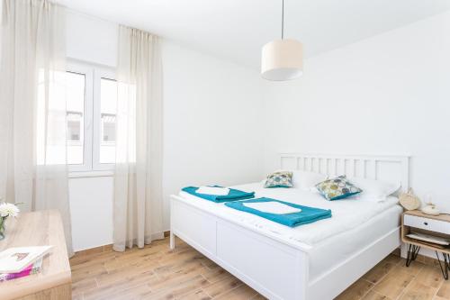 Dormitorio blanco con cama con almohadas azules en Apartments by the sea Pisak, Omis - 21568, en Pisak