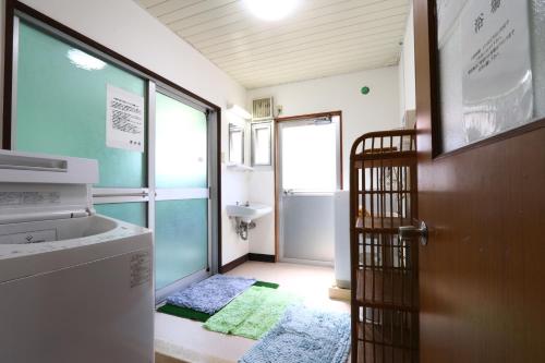 łazienka z drzwiami, umywalką i pralką w obiekcie Suikoen w mieście Yonago