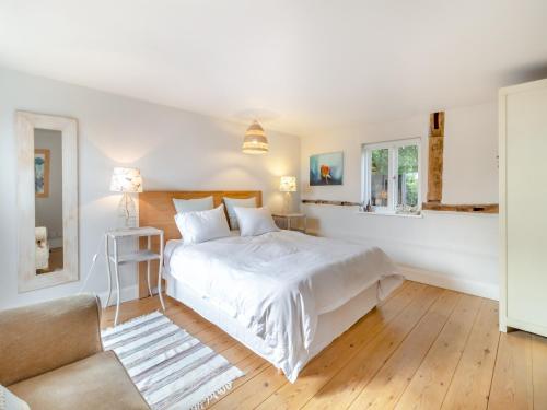 a white bedroom with a large bed and a chair at Linen Post Barn in Debenham
