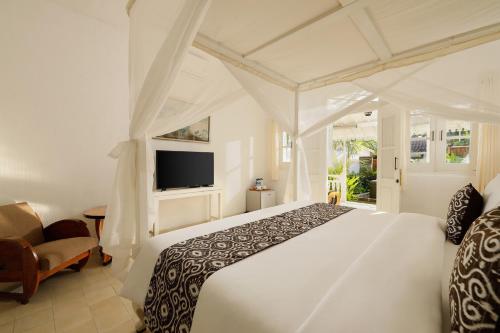 a bedroom with a large white bed and a tv at Puri Tempo Doeloe Boutique Hotel in Sanur