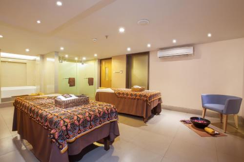 a hotel room with two beds and a blue chair at de Vins Sky Hotel Seminyak in Seminyak
