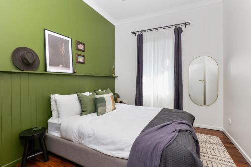 Dormitorio verde con cama y espejo en The Oyster Shack en Nambucca Heads