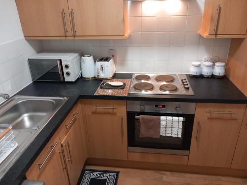 a kitchen with a stove top oven next to a sink at Heronsgate GH015 in Gravesend