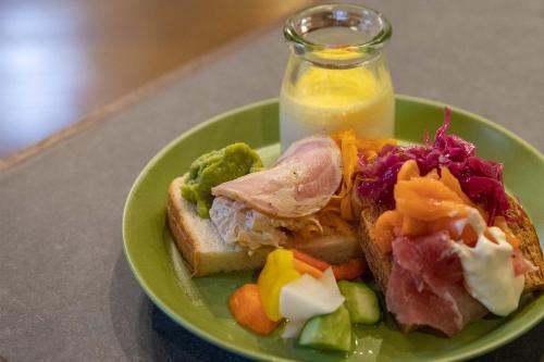 a green plate with a sandwich and a bottle of milk at Hotel Crescent Asahikawa in Asahikawa