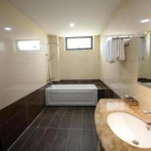 a bathroom with a bath tub and a sink at Quê Tôi Hotel in Soc Trang
