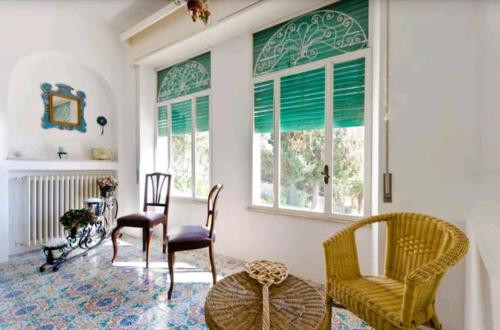 a living room with chairs and a table and windows at Villa Moschella in Taormina