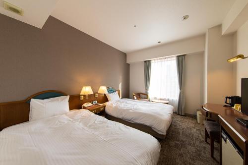 a hotel room with two beds and a television at Hotel Crescent Asahikawa in Asahikawa