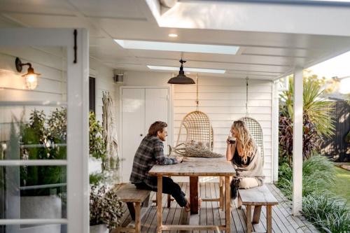 two people sitting at a table on a porch at Soul of Gerringong Cottage in Gerringong