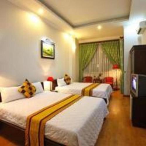 a hotel room with two beds and a television at Quê Tôi Hotel in Soc Trang