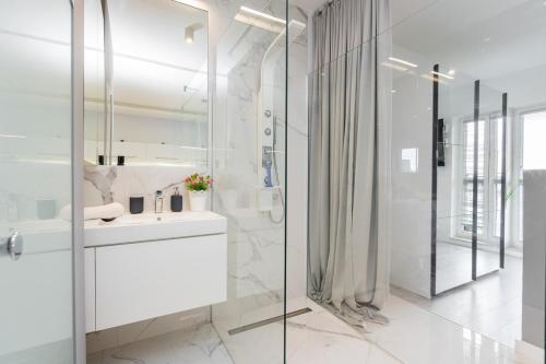a white bathroom with a sink and a shower at Wagonowa Premium Studio Chopin Airport in Warsaw