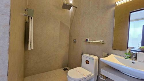 a bathroom with a sink and a toilet and a mirror at Lotus Colombo Guesthouse in Colombo