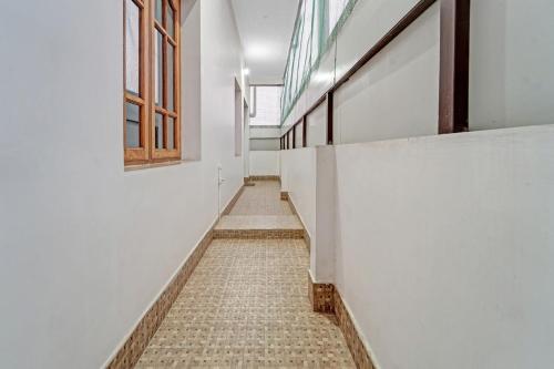 un couloir d'un bâtiment avec des murs et des fenêtres blancs dans l'établissement Collection O Ark Residency, à Irugūr