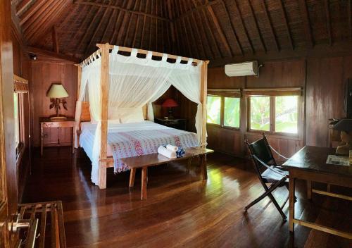a bedroom with a canopy bed and a wooden floor at Kolonial House in Sanur