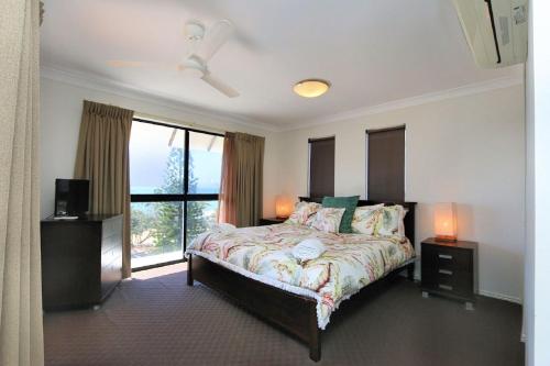 a bedroom with a bed and a large window at Coral Sands Penthouse in Bargara