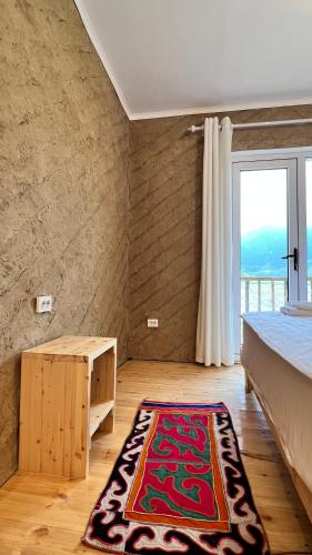 a bedroom with a bed and a rug on the floor at Altay Village Hotel in Orto-Saz