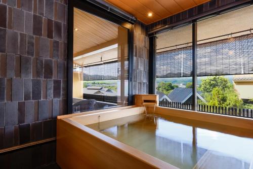 a large bath tub in a room with large windows at Kyoto Arashiyama Onsen Ryokan Togetsutei in Kyoto