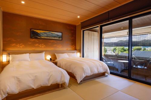 a bedroom with two beds and a large window at Kyoto Arashiyama Onsen Ryokan Togetsutei in Kyoto