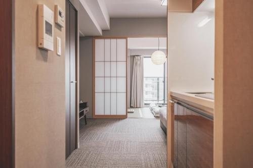 a hallway with a door leading to a kitchen with a window at Chuan House Dotonbori in Osaka