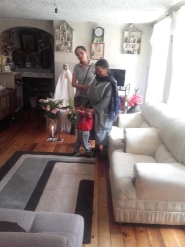 dos personas de pie en una sala de estar junto a un sofá en casa completa en alquiler, en Quito