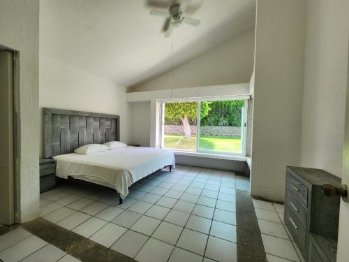 1 dormitorio con cama y ventana grande en Club de golf Santa Fe: amplia casa en el mejor clima, en Alpuyeca