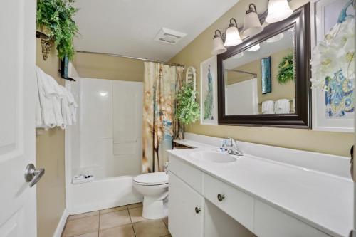 a bathroom with a sink and a toilet and a tub at Shores of Panama 1912 in Panama City Beach