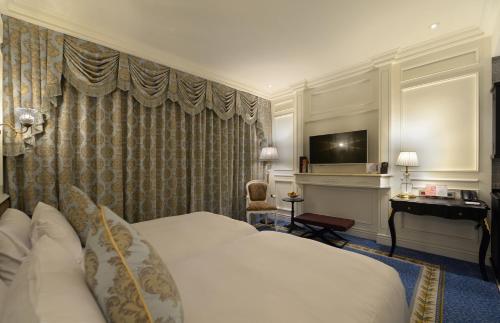 a hotel room with a bed and a television at Golden Tulip RS Boutique Hotel-Tainan in Tainan