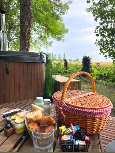 a picnic table with bread and a basket on it at La Ferme 1851 - Cabane Spa Nordique privé vue sur champ in Willems