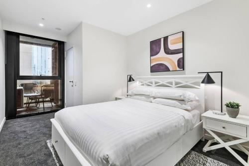 een witte slaapkamer met een groot bed en een raam bij Slate Skies at Palladium - Urban Lifestyle with Pool in Melbourne