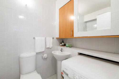 uma casa de banho branca com um WC e um lavatório em 'Melbourne Chic on Russell' Cosy City Living em Melbourne