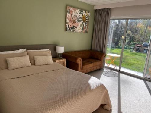 Riverbank Park MOTEL في برايت: غرفة نوم بسرير واريكة ونافذة