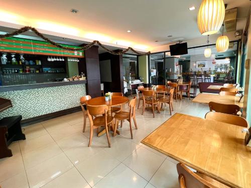 a restaurant with wooden tables and chairs and a bar at Srivichai Hotel in Nakhon Ratchasima