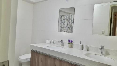 a white bathroom with two sinks and a toilet at Exclusivo Hospedaje Moore in Lima