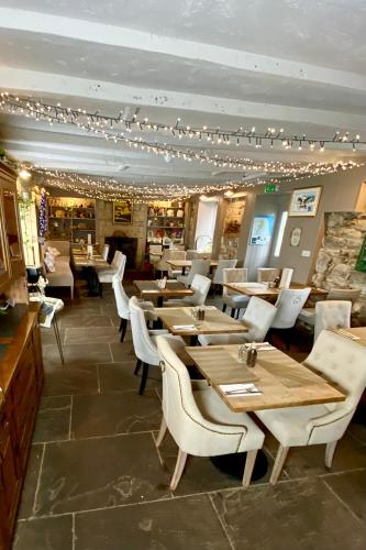 a restaurant with wooden tables and white chairs at Bird In Bush Elsdon in Elsdon