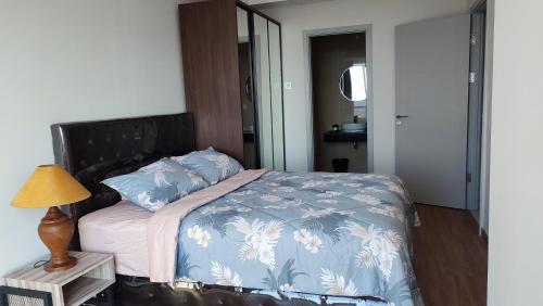 a bedroom with a bed with a blue comforter and a lamp at DeAr Caspian Apartment in Surabaya